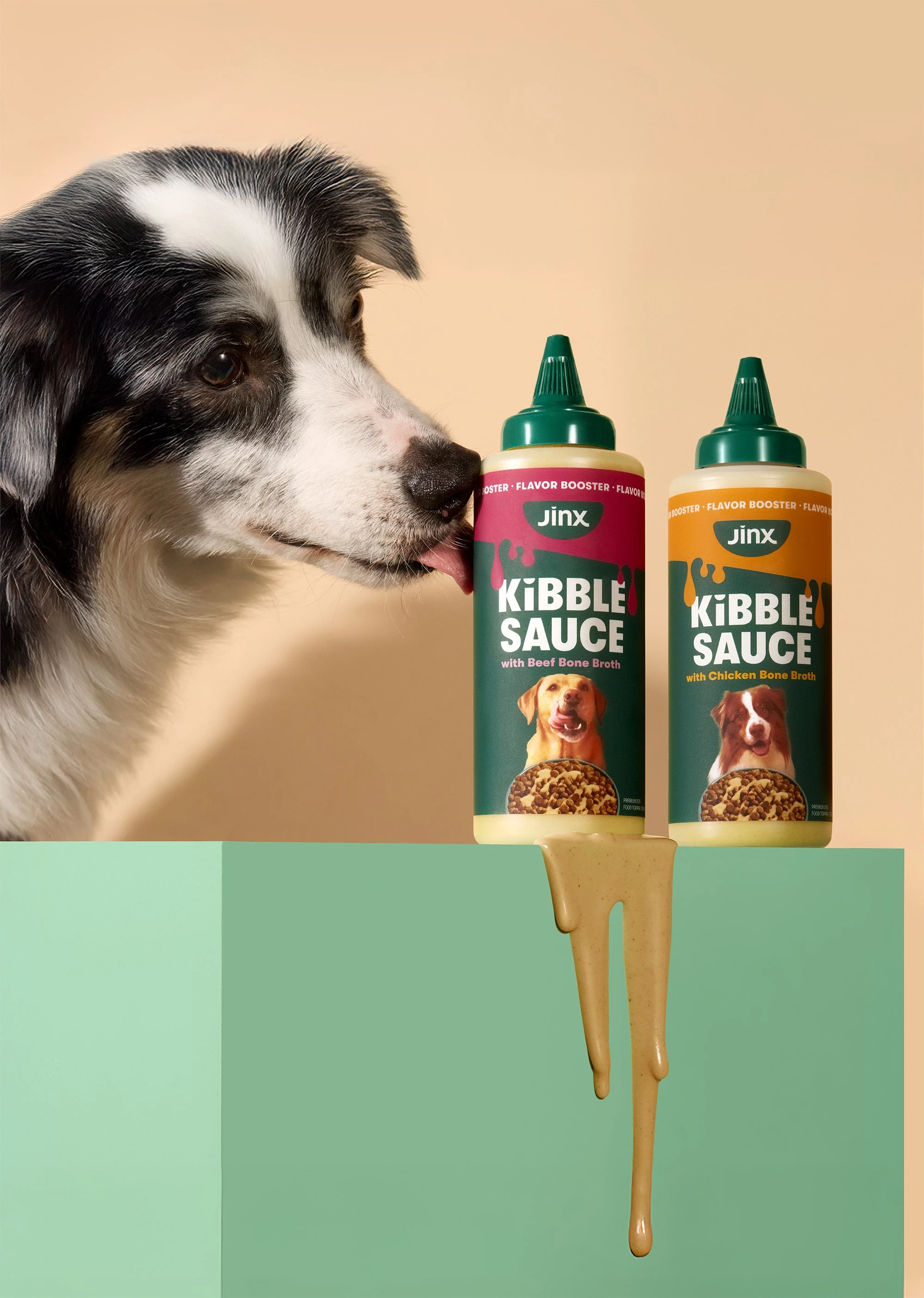 A dog sniffs two squeeze bottles of Jinx Kibble Sauce