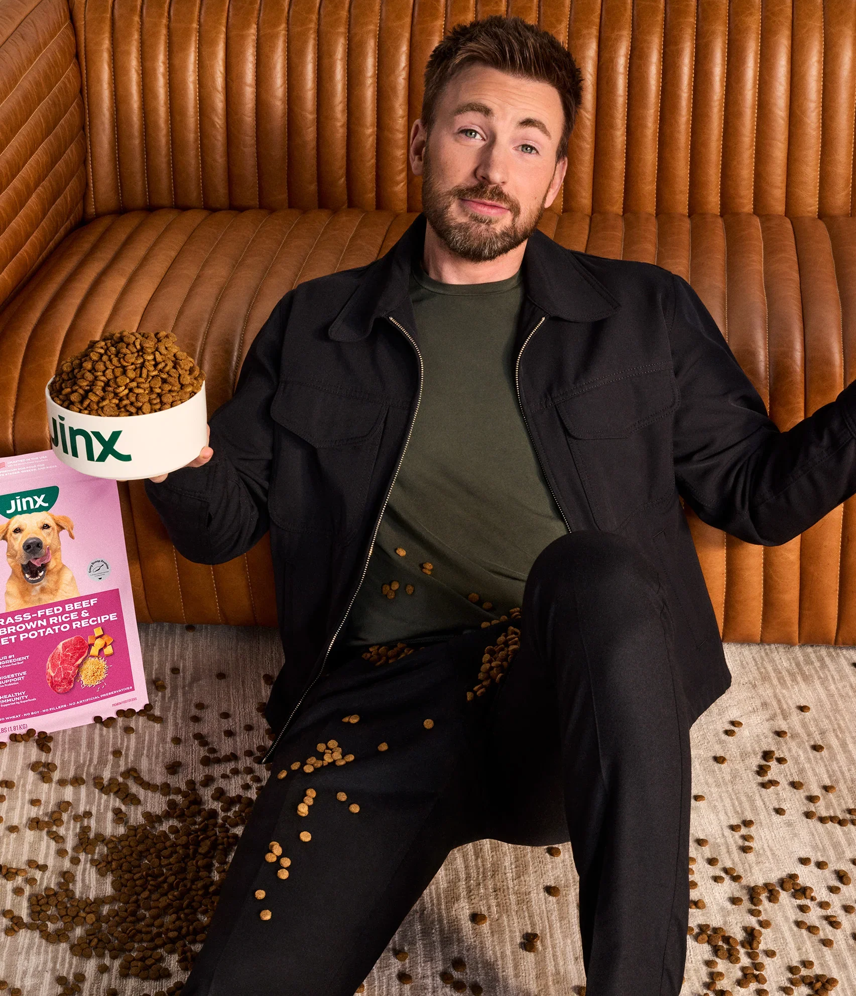 Chris Evans sitting on the ground shrugging, covered in Jinx kibble